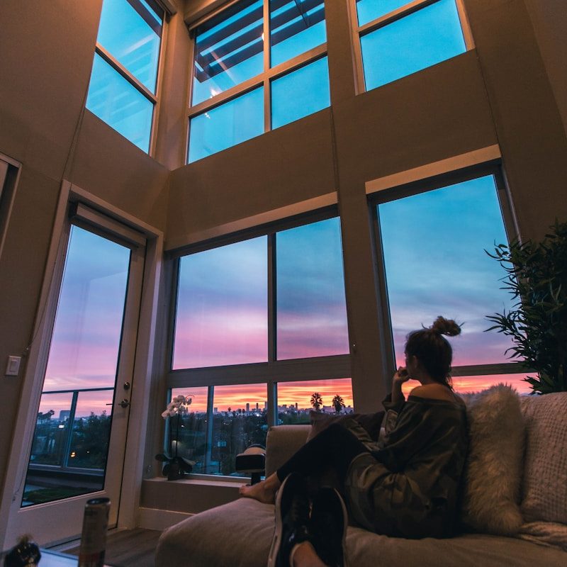 a person sitting on a couch looking out a window